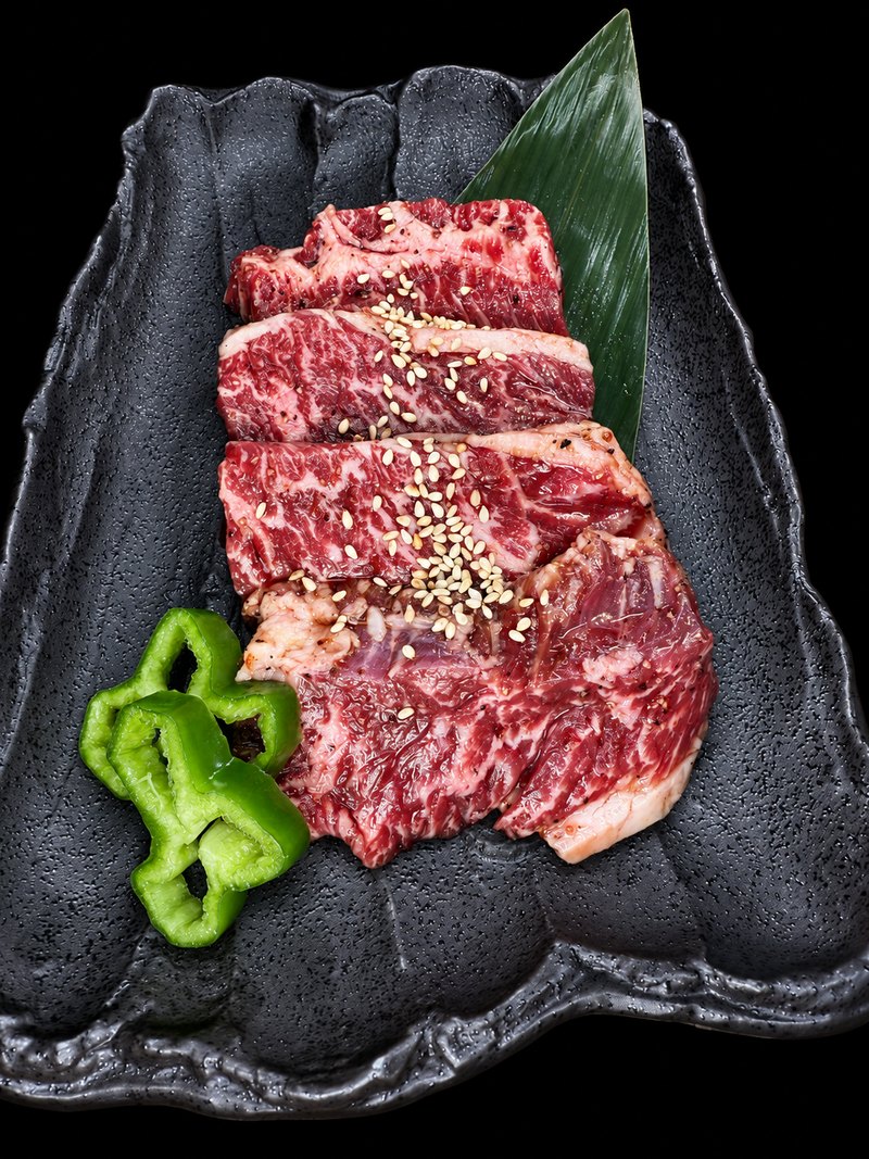 黒い角皿に、白ごまを振った肉を等間隔に並べた一皿
