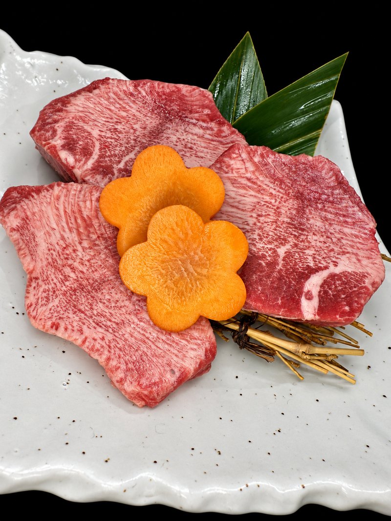 白い角皿に、霜降りの大きな肉を二枚広げ、にんじんの飾り切りを添えた一皿