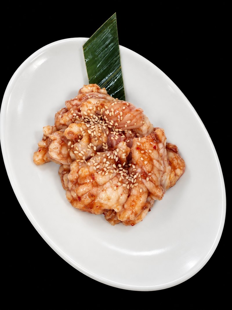 白い楕円皿に、たれをからめ白ごまを振った肉を盛り付けた一皿