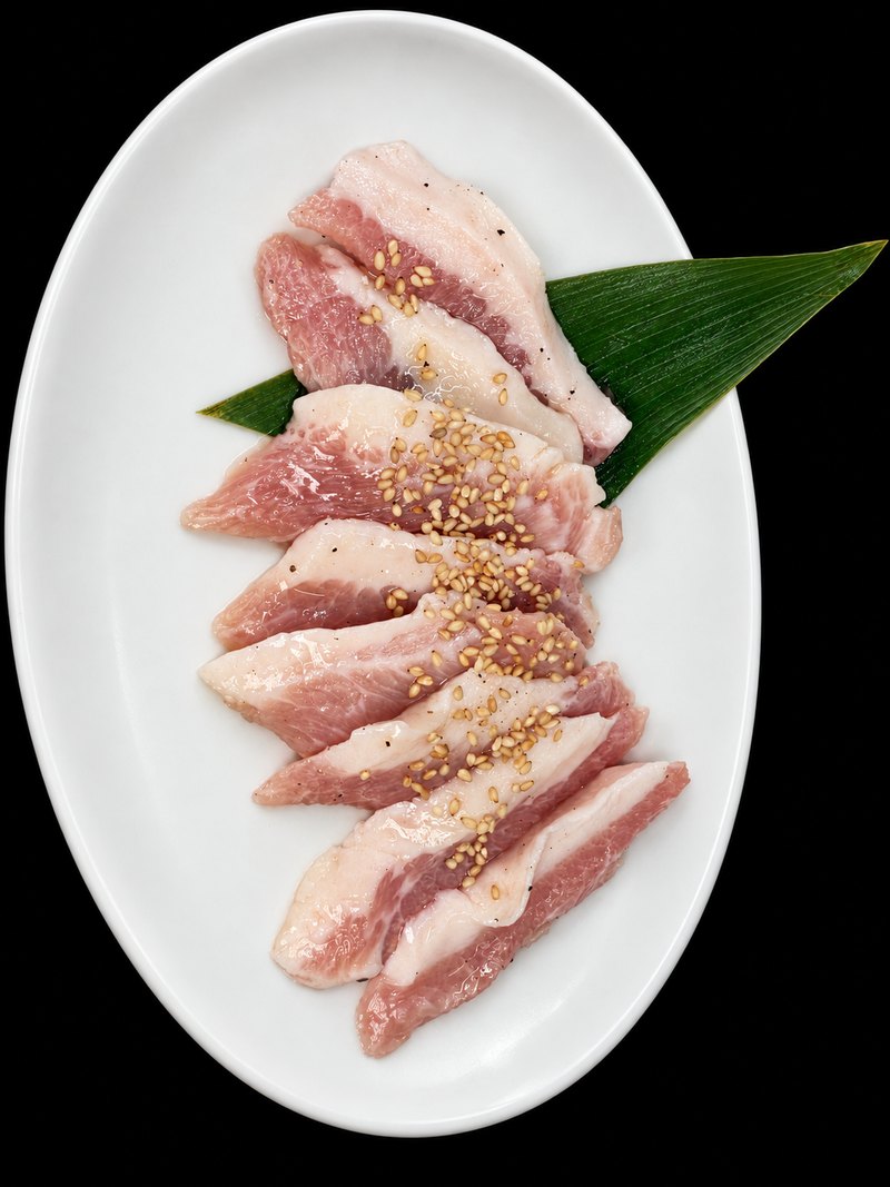 白い楕円皿に、白い脂の多い肉を並べ、ごまを振った一皿