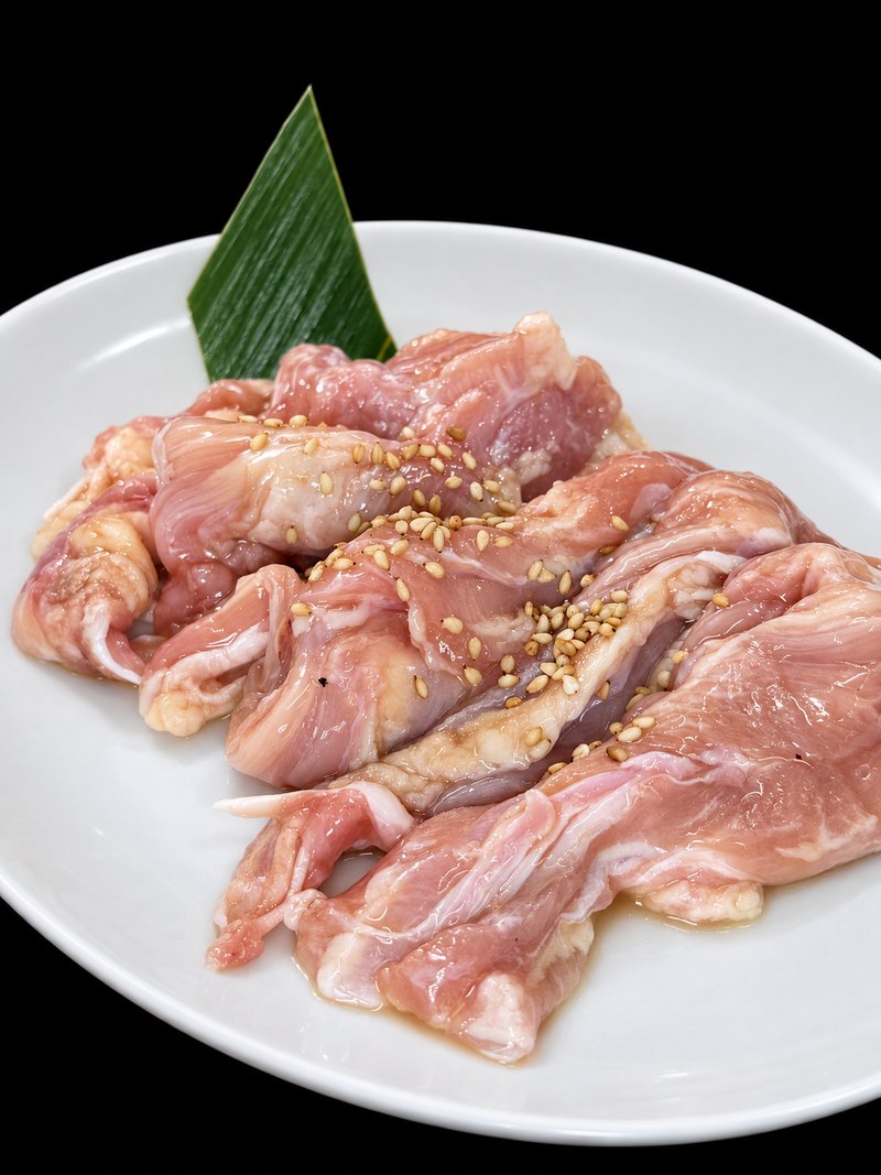 白い楕円皿に、淡い色の肉を重ねて盛り付けた一皿